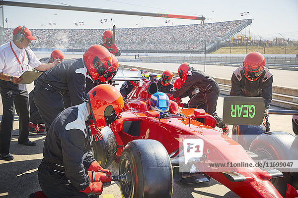 Pit crew replacing tires on formula one race car in pit lane practice session