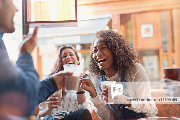 Lachende junge Freunde trinken Milchshakes im Cafe