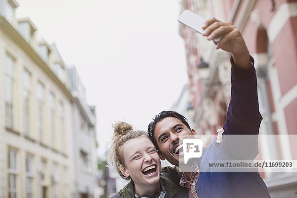Begeistertes  lachendes junges Paar macht Selfie in der Stadt