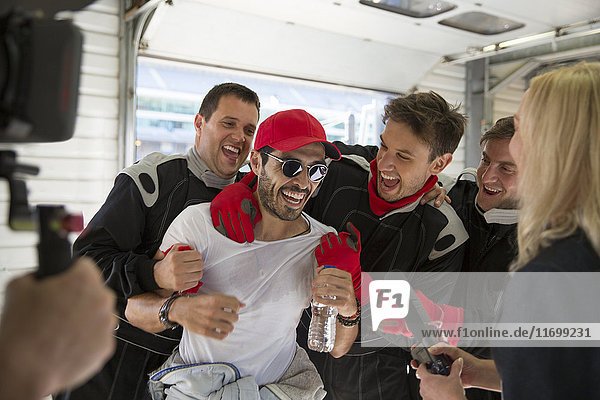 Formula one driver and team celebrating victory in repair garage