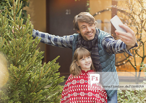 Vater und Tochter nehmen Selfie mit Weihnachtsbaum außerhalb des Hauses