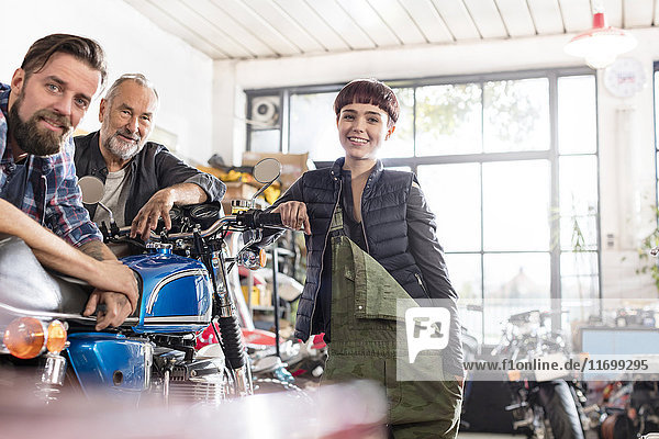 Portrait smiling male and female motorcycle mechanics in workshop