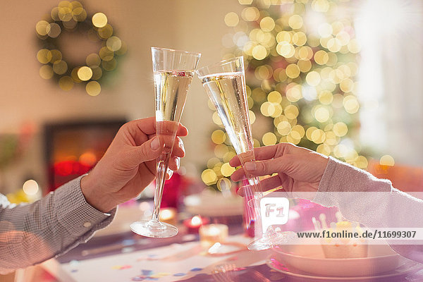 Ehepaar stößt mit Champagnerflöten am Weihnachtstisch an