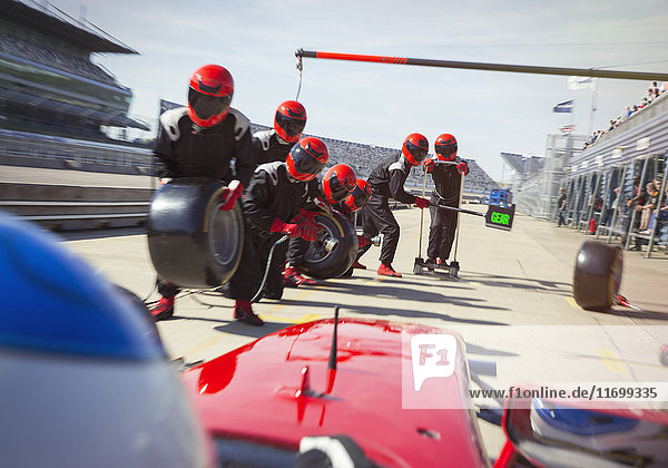 Boxencrew mit Reifen bereit für die Annäherung an Formel 1-Rennwagen in der Boxengasse