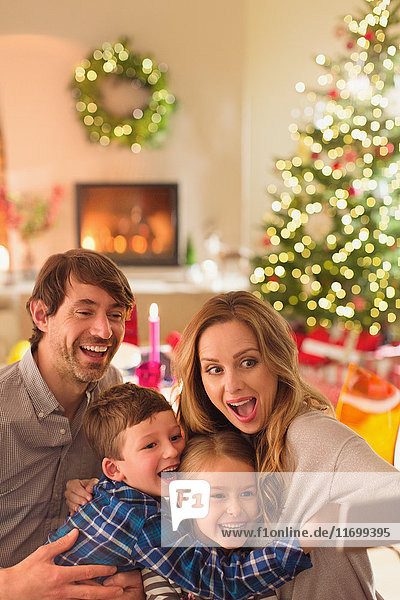 Silly family taking selfie with camera phone in Christmas living room