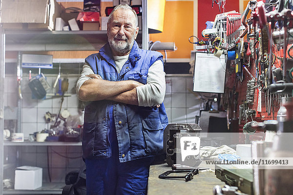 Portrait confident senior male motorcycle mechanic in workshop
