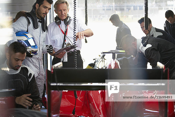 Manager und Formel-1-Fahrer bei der Arbeit am Rennwagen in der Reparaturwerkstatt