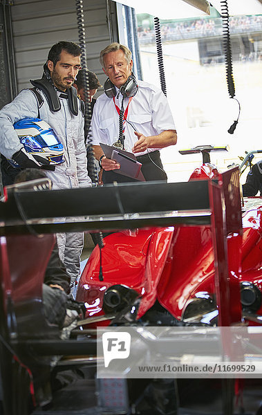 Manager und Formel-1-Rennfahrer im Gespräch in der Werkstatt