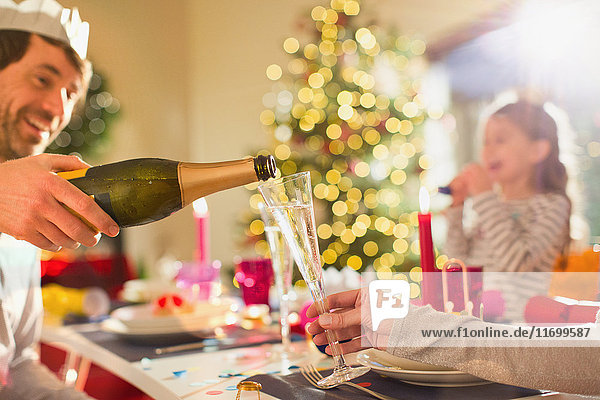 Ehemann schenkt seiner Frau beim Weihnachtsessen Champagner ein