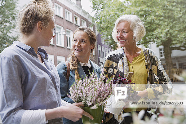 Florist showing plants to mother and daughter at storefront