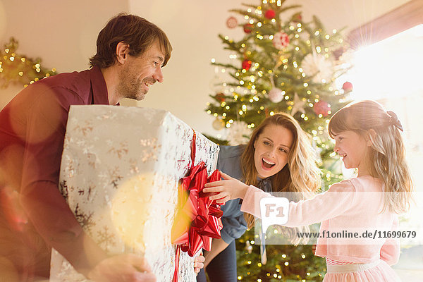 Eltern schenken ihrer Tochter ein großes Weihnachtsgeschenk unter dem Weihnachtsbaum