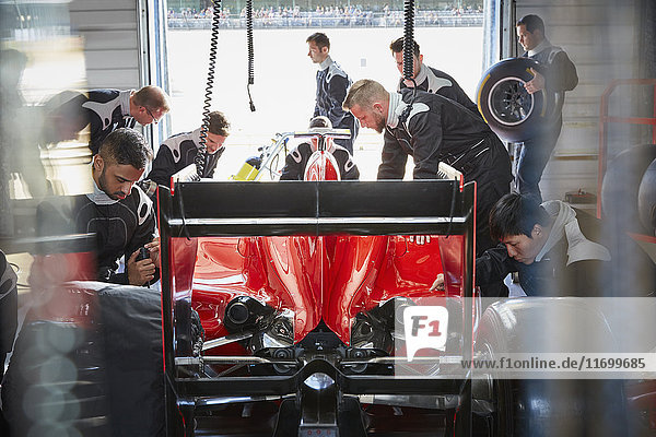 Pit crew preparing formula one race car in repair garage