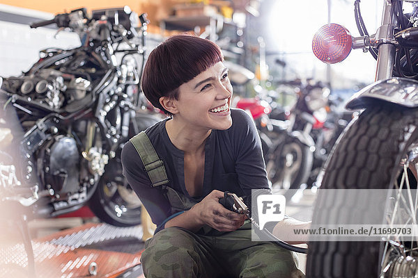 Enthusiastische Motorradmechanikerin bei der Motorradreparatur in der Werkstatt