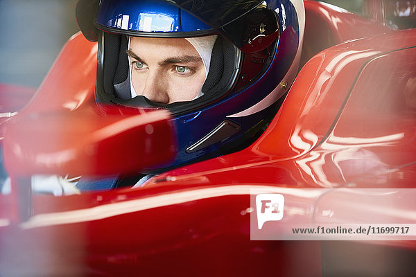Close up focused formula one driver wearing helmet in race car