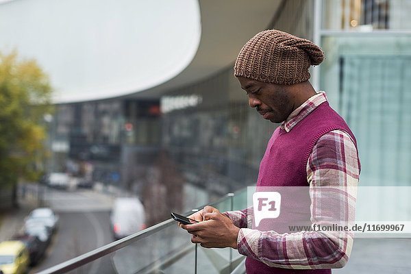 Mann steht auf der Terrasse mit dem Handy