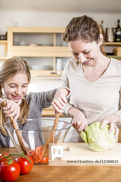 Mutter und Tochter kochen Salat in der Küche