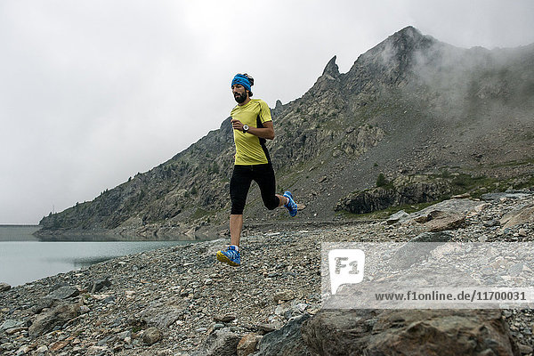 Italy  Alagna  trail runner on the move at a lake near Monte Rosa mountain massif