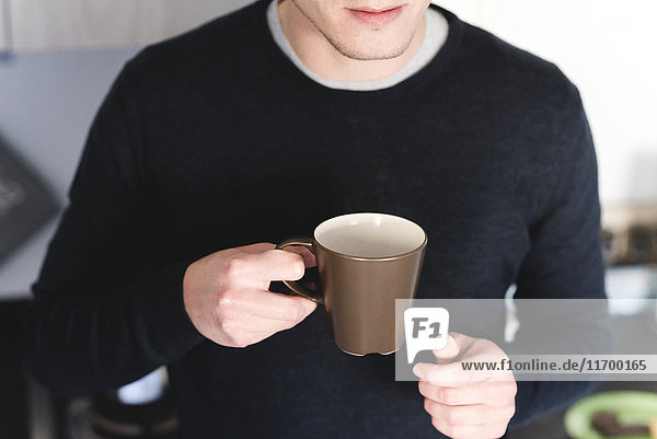 Mann mit Tasse Kaffee in der Küche,  Teilansicht
