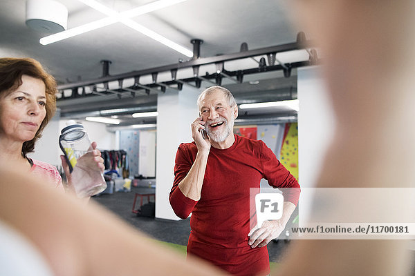 Fit Senior Mann mit Smartphone im Fitnessstudio