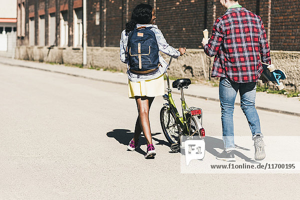 Junges Ehepaar mit Fahrrad und Skateboard auf der Straße