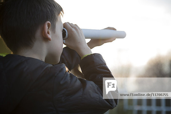 Boy watching something with home-made telescope