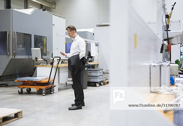 Businessman in factory shop floor looking on the phone