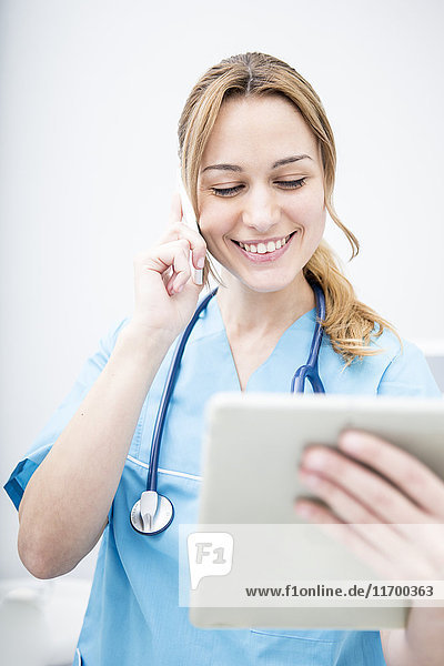 Smiling doctor on the phone looking at tablet