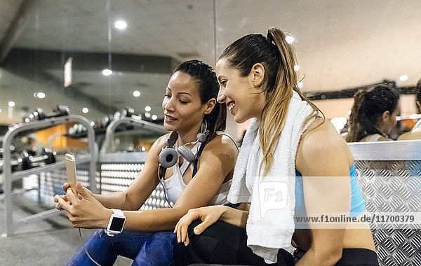 Zwei Frauen haben Spaß mit ihrem Smartphone nach dem Training im Fitnessstudio