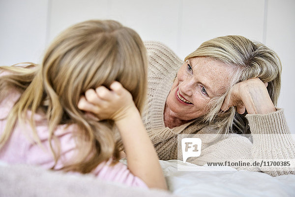 Seniorin entspannt mit ihrer Enkelin auf dem Bett