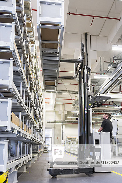 Worker operating forklift in factory warehouse