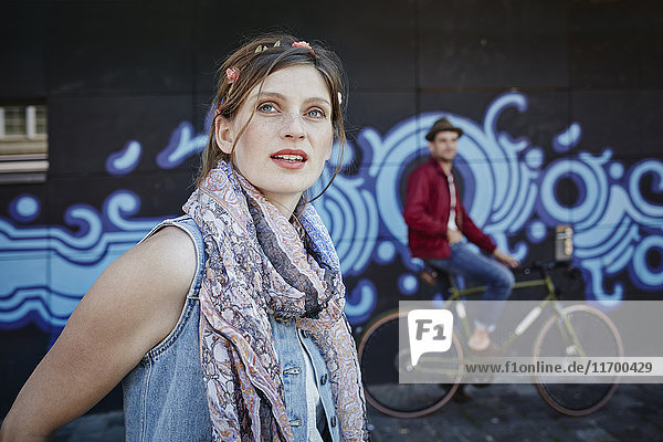 Deutschland  Hamburg  St. Pauli  Junge Frau und Mann auf dem Fahrrad vor Graffiti stehend