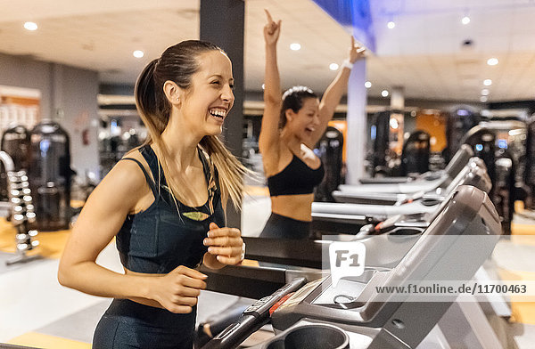 Zwei glückliche Frauen trainieren im Fitnessstudio auf einem Treadmil