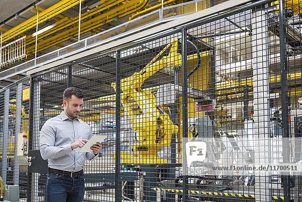 Mann mit Tablette in der Fabrikhalle