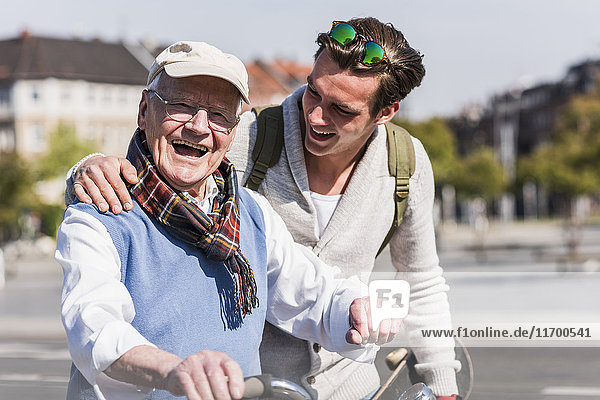 Glücklicher älterer Mann mit erwachsenem Enkel in der Stadt unterwegs