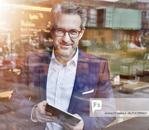 Confident mature businessman with tablet looking out of window
