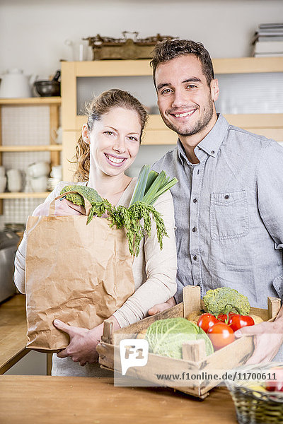 Lächelndes Paar mit Gemüsekiste in der Küche