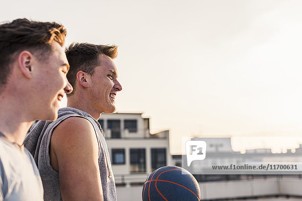 Freunde beim Basketball bei Sonnenuntergang auf einem Dach