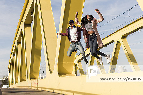 Glückliches Paar beim Springen auf der Brücke