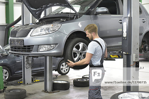 Car mechanic in a workshop changing car tyre