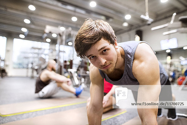 Porträt eines jungen Mannes  der im Fitnessstudio trainiert.