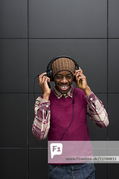 Porträt eines lächelnden Mannes beim Musikhören mit Kopfhörer und Handy