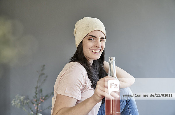Porträt einer lächelnden jungen Frau mit funkelnder Halteflasche