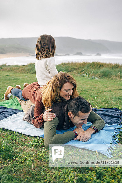 Glückliche Familie auf Decke an der Küste