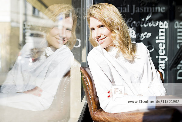 Lächelnde Geschäftsfrau in einem Café mit Blick aus dem Fenster