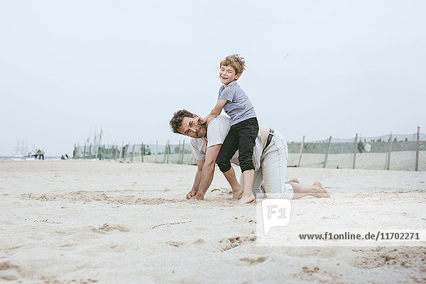 Vater und kleiner Sohn spielen zusammen am Strand.