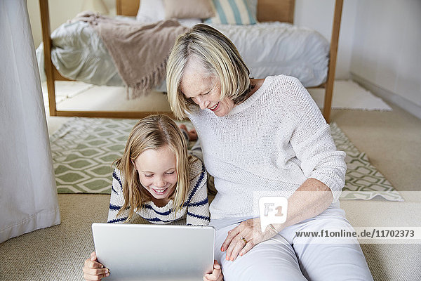 Little girl and her grandmother using tablet at home