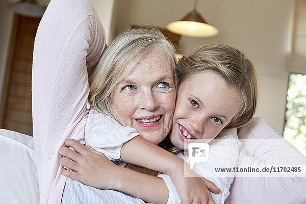 Porträt eines lächelnden kleinen Mädchens  das seine Großmutter umarmt.