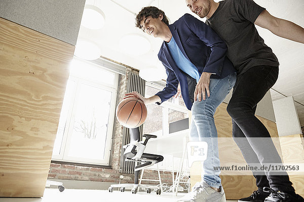 Junge Männer im Büro beim Basketballspielen
