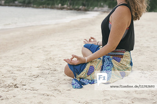 Frau beim Yoga am Strand