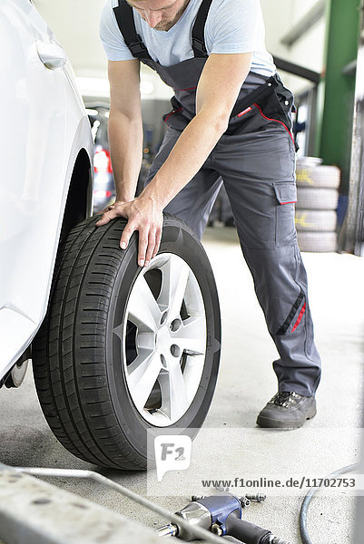 Car mechanic in a workshop changing car tyre